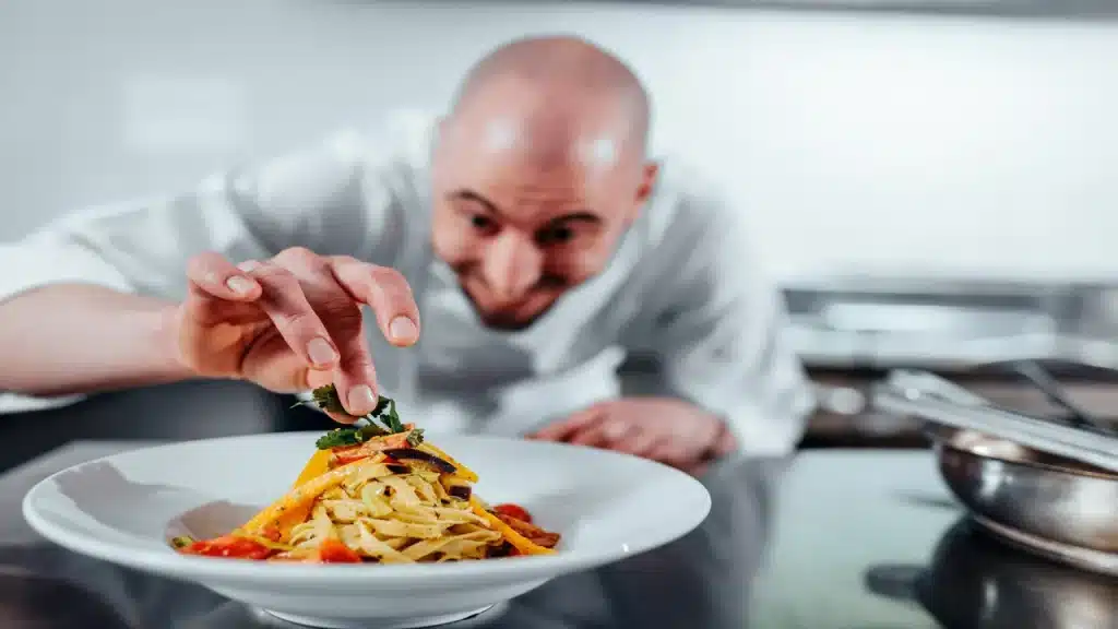 Chefe italiano montando um prato de macarrão representando a cozinha italiana.